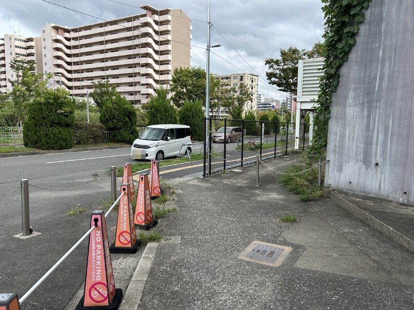 この道路沿いに車を停めてお待ちしております。手前のコーンのある敷地内ではなく、その先の道路沿いです。